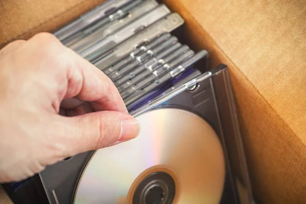 Hand taking out DVD or CD from a cardboard box. Close up.