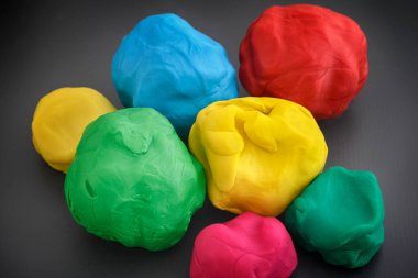 Colorful play clay balls on a dark gray background. Close up. clipart