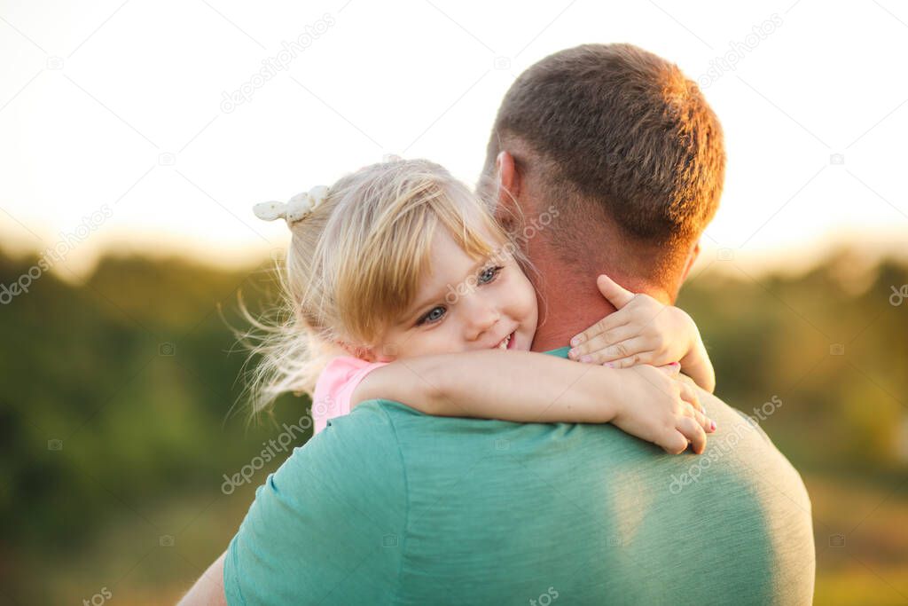 Little daughter hugs father tightly around the neck