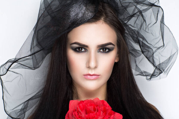 Creative image of a girl in a black veil and a large rose. Beauty portrait of a beautiful young woman lady model, beige lips smoky eyes. Professional makeup studio Prepare for party masquerade Brazil