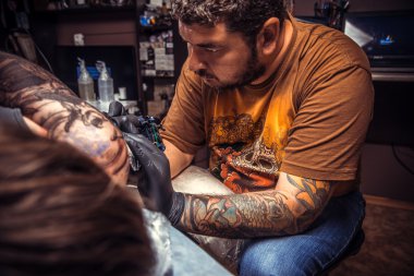 Tattoo specialist working tattooing in tattoo studio clipart