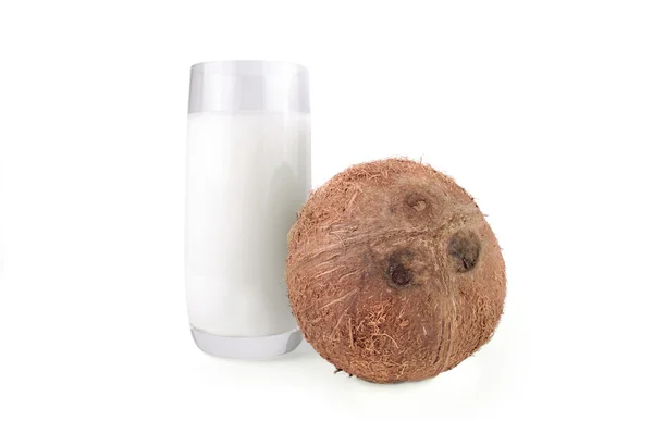 Coco entero y leche en un vaso sobre fondo blanco aislado — Foto de Stock