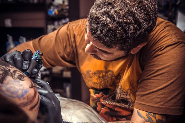 Tattooer makes tattoo in tatoo salon — Stock Photo, Image