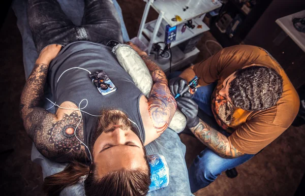 Tattoo specialist making a tattoo in tatoo salon — Stock Photo, Image