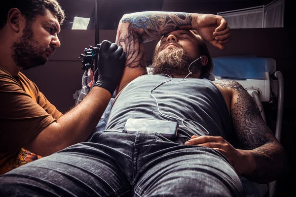 Artista profesional del tatuaje haciendo un tatuaje en el salón de tatuajes —  Fotos de Stock