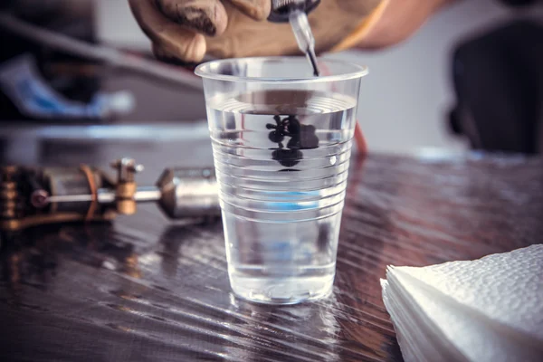 Tattoo master washes the machine gun — Stock Photo, Image