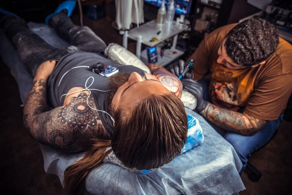 Tattoo master showing process of making a tattoo in tattoo studio — Stock Photo, Image