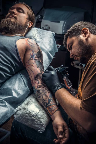 Мастер татуировки показывает процесс создания татуировки в тату-салоне — стоковое фото