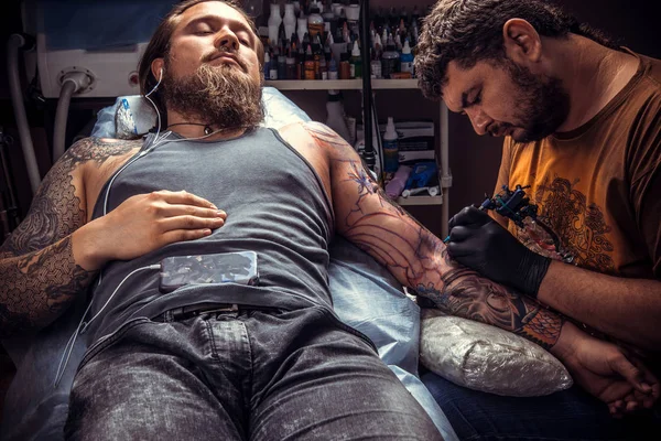 Tattoo specialist showing process of making a tattoo in tattoo studio — Stock Photo, Image