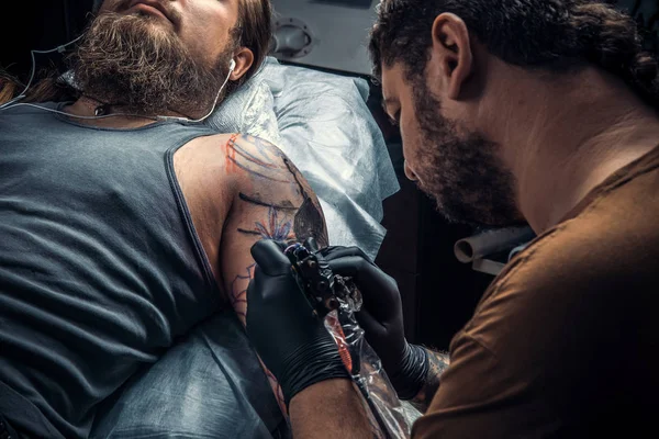 Professional tattooer create tattoo in salon./Professional tattooist showing process of making a tattoo in tattoo parlor.