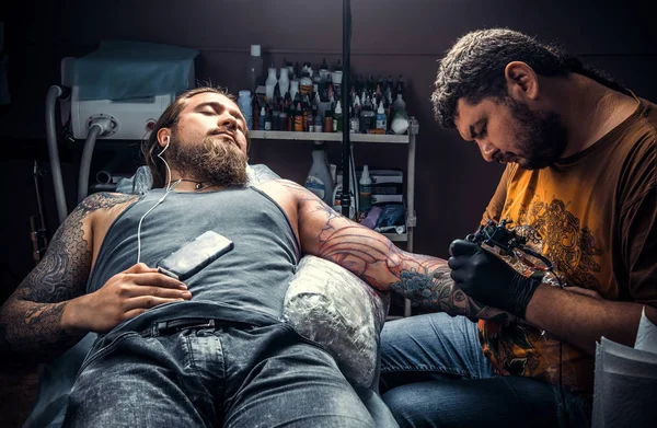 Professional tattooer making a tattoo in tattoo studio./Professional tattooist doing tattoo in tattoo parlor.