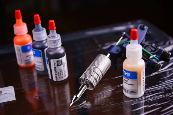 tattoo gun and vials with different colored ink for tattoos