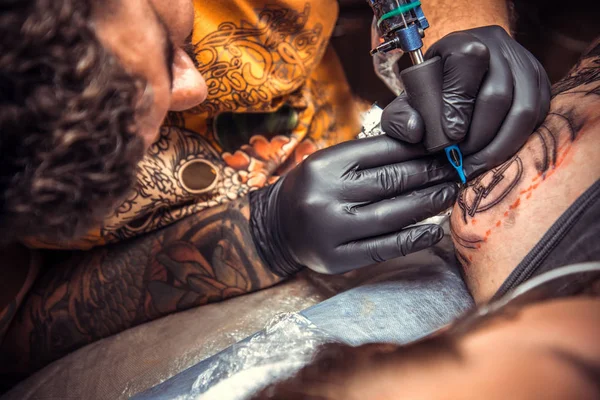 Professional tattooer makes tattoo in tattoo parlor — Stock Photo, Image