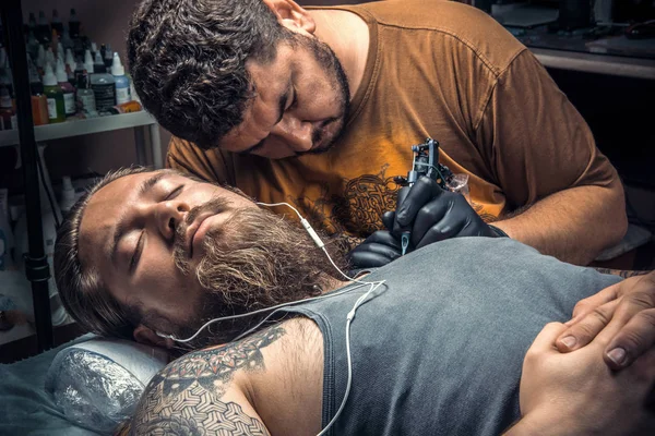 Especialista en tatuajes que muestra el proceso de hacer un tatuaje en el salón de tatuajes —  Fotos de Stock