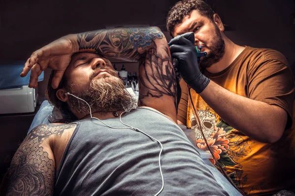 Master doing tattoo in tattoo studio./Tattoo specialist posing in tattoo parlour.