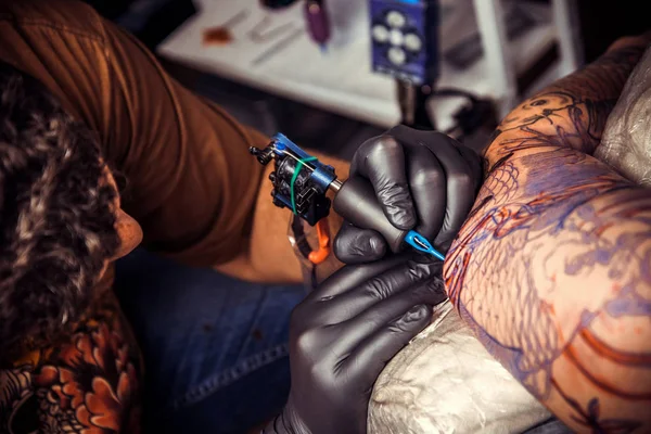 Tattooer at work in tattoo studio./Professional tattooist create tattoo in tattoo parlor.