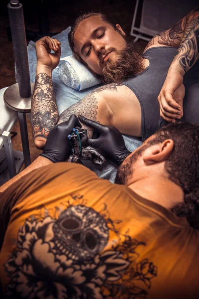 Tattooer showing process of making a tattoo in tattoo studio — Stock Photo, Image
