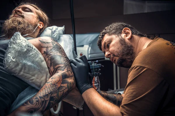 Artista de tatuagem profissional trabalhando tatuagem em sala de tatuagem — Fotografia de Stock