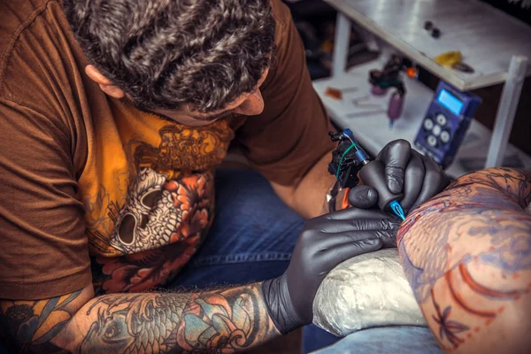 Tattoo master showing process of making a tattoo in tattoo parlor — Stock Photo, Image