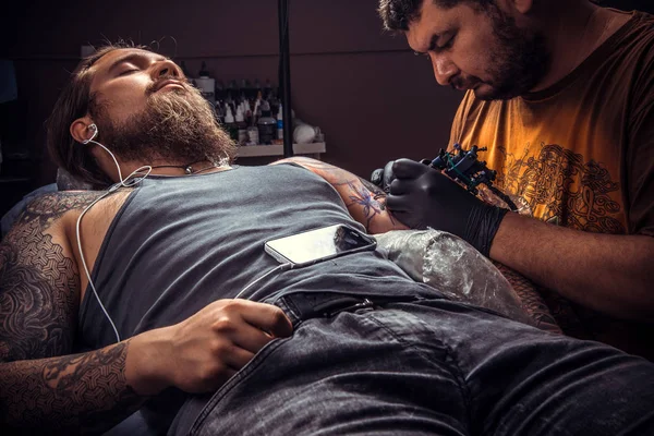 Professionell tattooer gör tatuering i tatuerare — Stockfoto