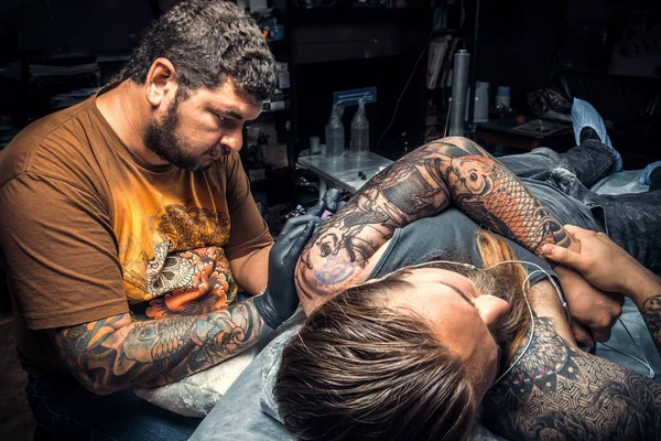 Tattoo master showing process of making a tattoo in tattoo studio