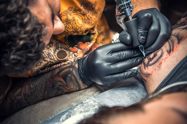 Professional tattooist showing process of making a tattoo in studio — Stock Photo, Image