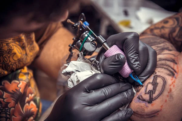 Professional tattooist doing tattoo in studio