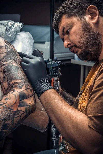 Professional tattooist create tattoo in tattoo parlour./Master makes cool tattoo in salon.