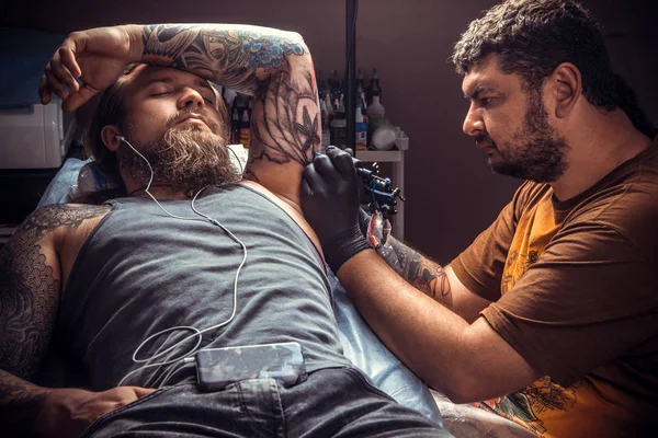 Master create tattoo in tattoo studio./Professional tattooist at work in tattoo studio.