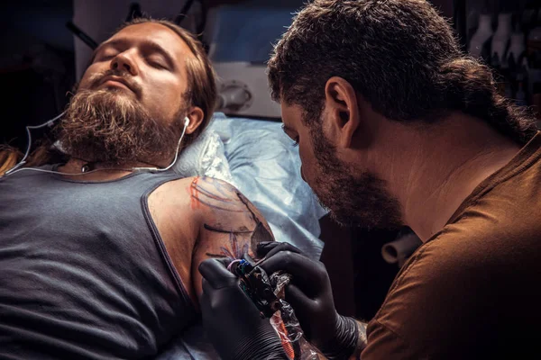 Специалист по татуировкам делает татуировку в студии — стоковое фото