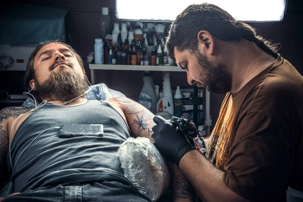 Professional tattooer posing in tattoo studio./Master makes cool tattoo in tattoo studio.