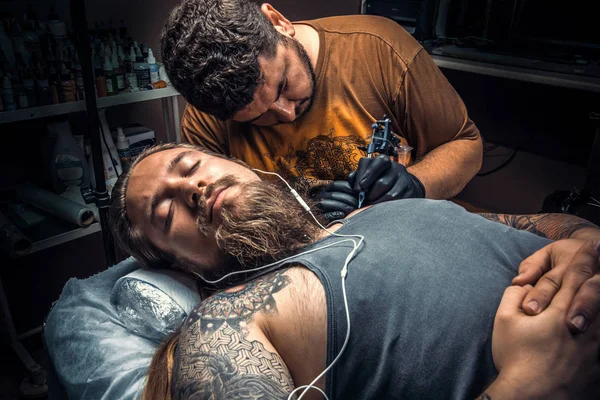 Professional tattooist showing process of making a tattoo in studio — Stock Photo, Image