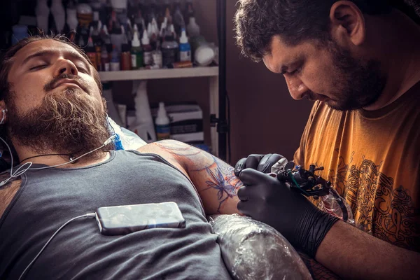 Professional tattooist posing in tattoo studio./Professional tattooer works in tattoo parlor.