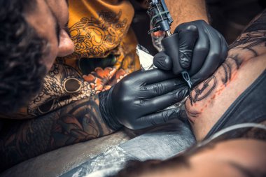 Tattooer working tattooing in tattoo studio clipart