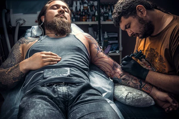 Especialista em tatuagem fazendo uma tatuagem em sala de tatuagem — Fotografia de Stock