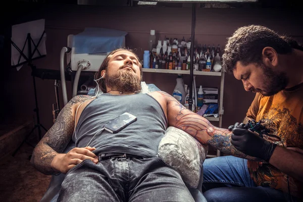 Tattoo master create tattoo in studio./Professional tattooist at work in tattoo parlour.