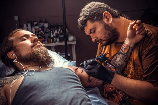 Tattoo master making a tattoo in tattoo parlor — Stock Photo, Image