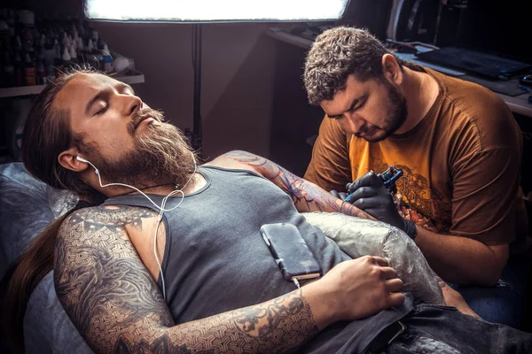 Professional tattoo artist making a tattoo in tattoo studio