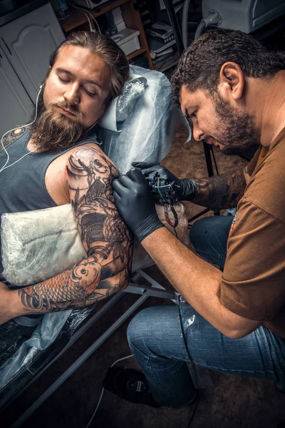 Tatuagem mestre mostrando processo de fazer uma tatuagem em sala de tatuagem — Fotografia de Stock
