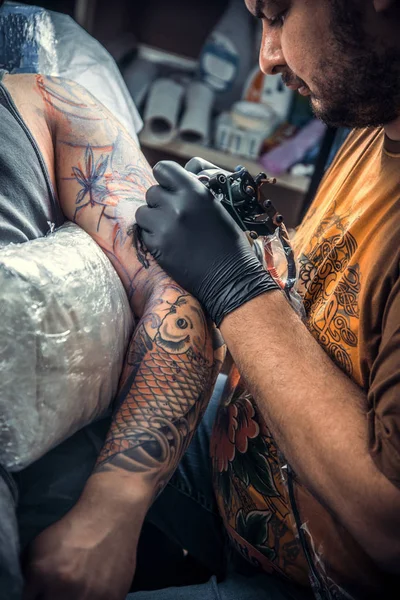 Профессиональный татуировщик работает в тату-студии — стоковое фото
