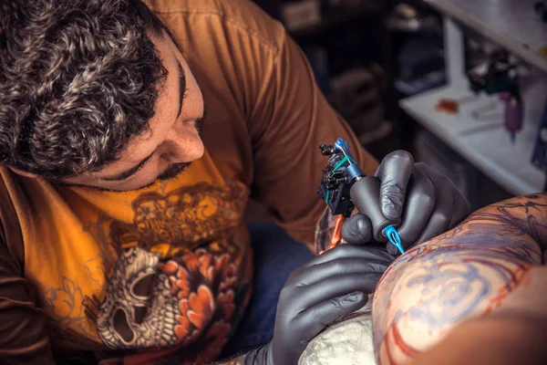 Mestre de tatuagem faz imagens de tatuagem em sala de tatuagem — Fotografia de Stock