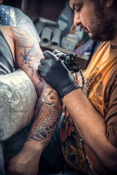 Especialista em tatuagem fazendo tatuagem em sala de tatuagem — Fotografia de Stock