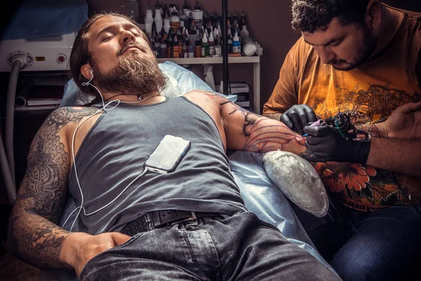 Professional tattoo artist posing in tattoo studio./Tattoo specialist makes tattoo pictures in tattoo studio.