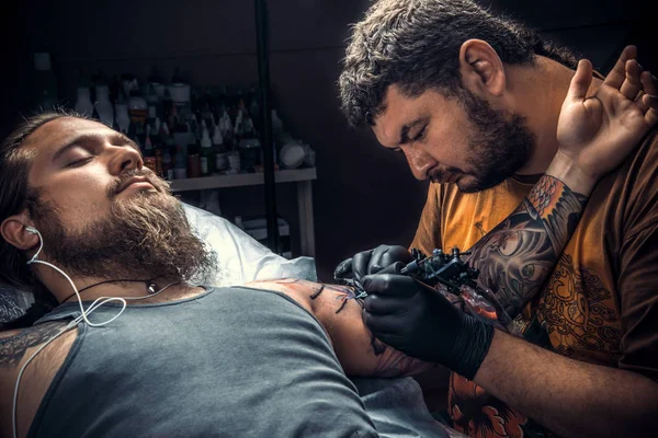 Artista de tatuagem profissional mostrando o processo de fazer uma tatuagem na sala de tatuagem — Fotografia de Stock