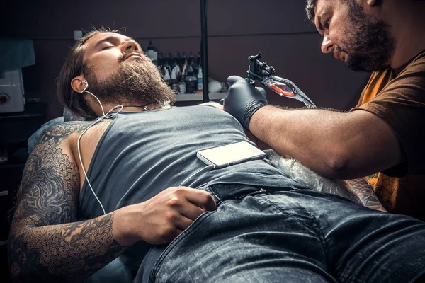 Tattoo master makes tattoo in tattoo studio
