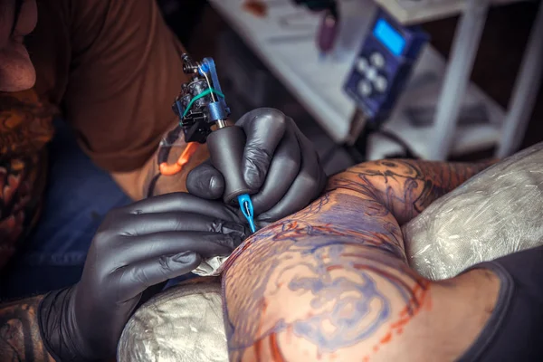 Tattoo master makes tattoo in tattoo parlor — Stock Photo, Image