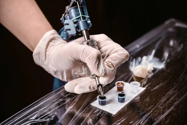 Tatuagem profissional está ganhando o corante em uma máquina de tatuagem — Fotografia de Stock