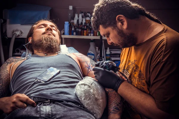 Ammattimainen tatuoija tekee tatuoinnin studiossa — kuvapankkivalokuva