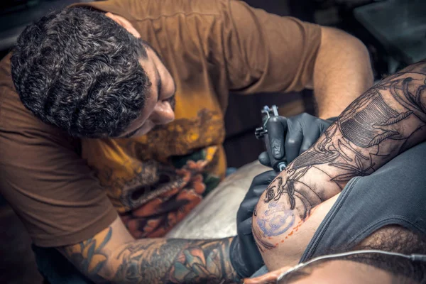 Mestre de tatuagem fazendo tatuagem no salão de tatuagem — Fotografia de Stock
