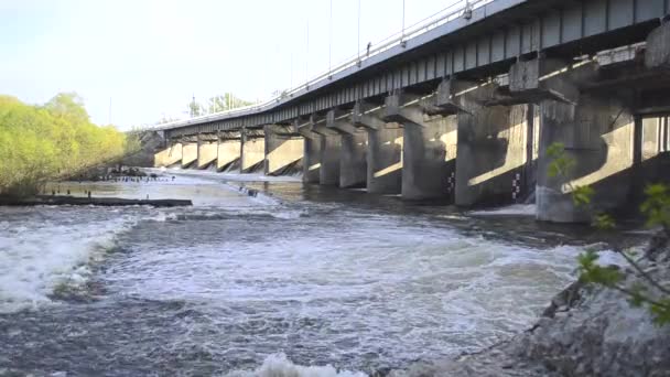 Lente ingestroomd water stroomt op waterkrachtcentrale dam — Stockvideo